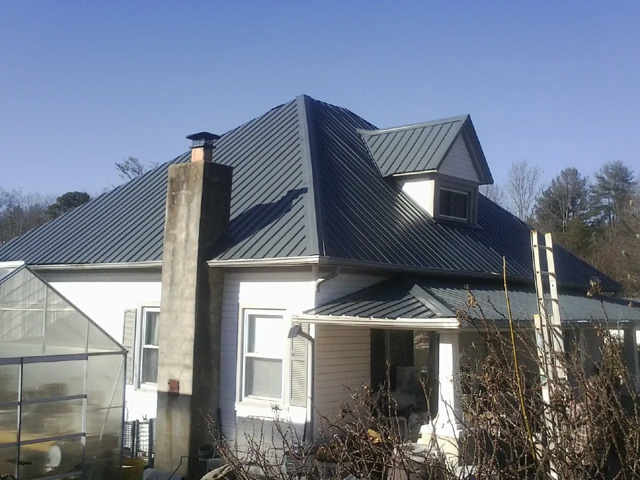 Dark blue standing seam metal roof on a white farmhouse with dormer — Slate & Tile Roof Repair by Roofing Brothers in Manville