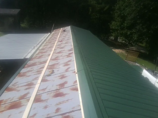 Old rusted panels beside newly installed green metal roofing — Wind Damage Roof Repair by Roofing Brothers in Manville